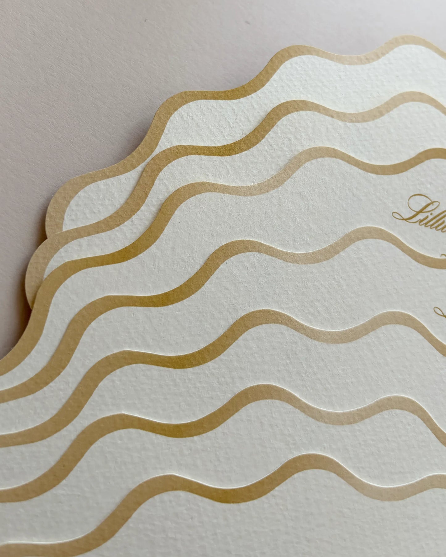 A close-up view of the decorative edge of a luxury fan wedding order of the day, showcasing elegant embossed wavy gold foil lines on high-quality cream textured paper — Polina Perri