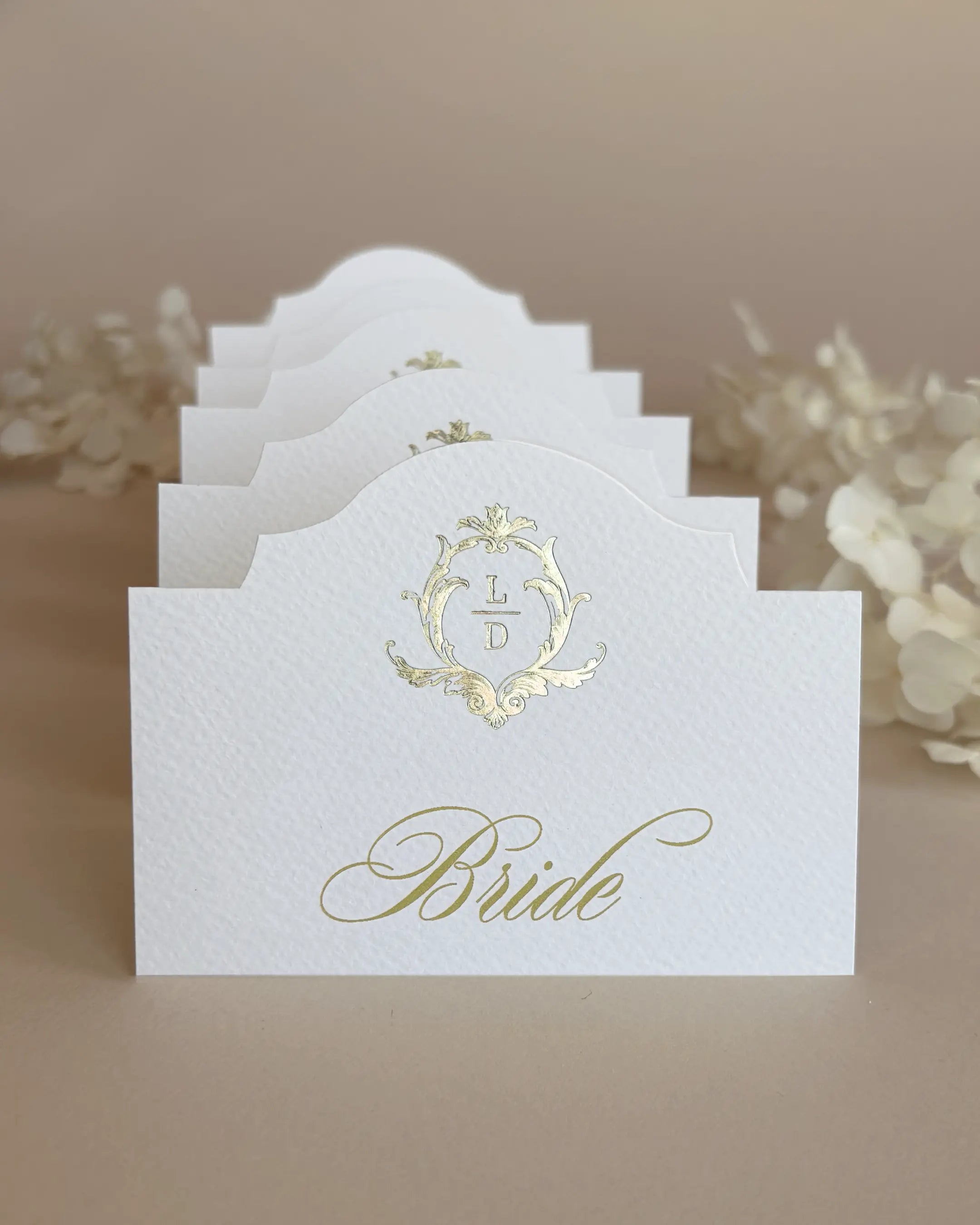 White Elegant Arch Place Cards with gold foil crest stacked in a row showing arch silhouette — Polina Perri