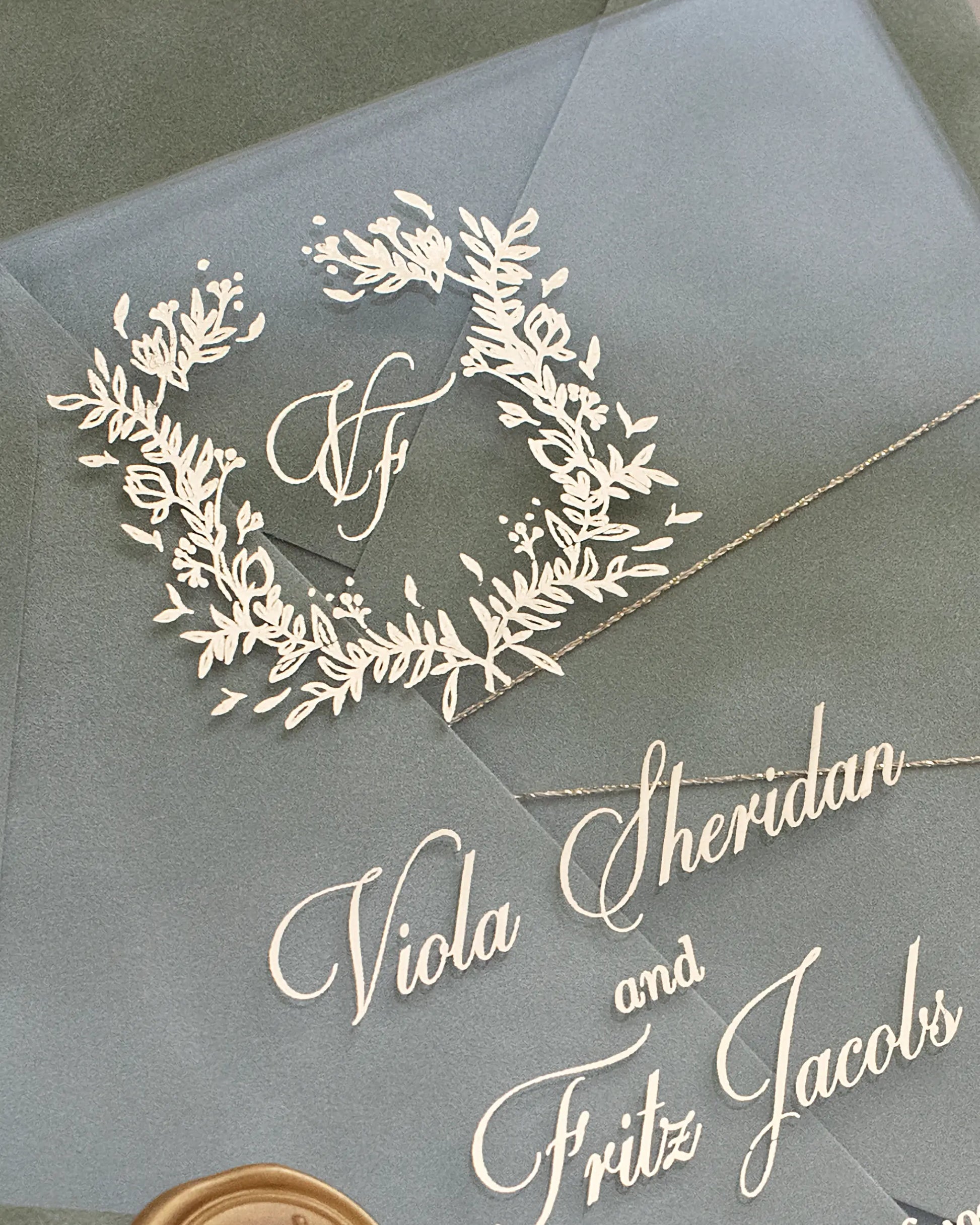 Fiori Acrylic Wedding Invitation close-up with white foil botanical wreath and script calligraphy names — Polina Perri