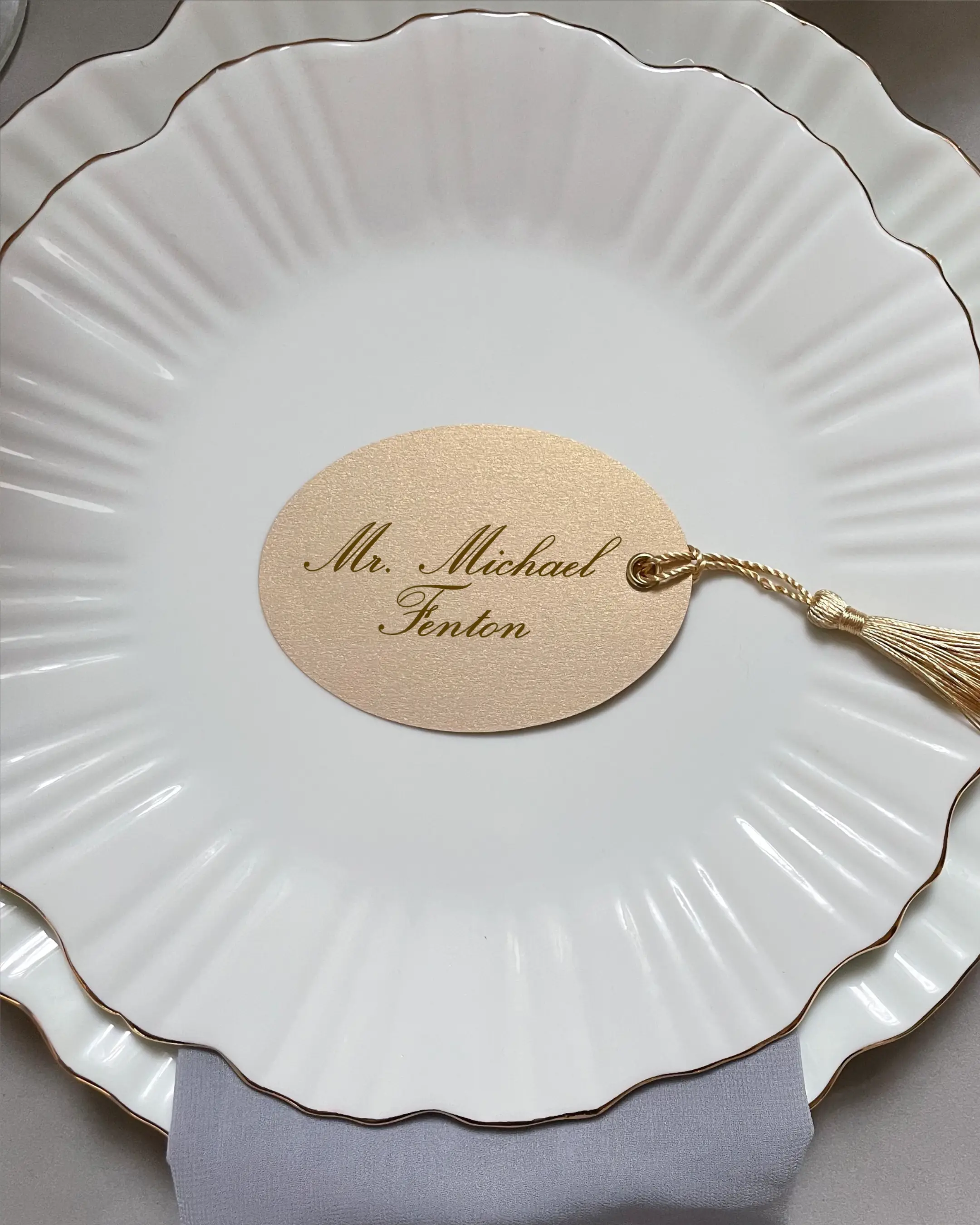 Cream Oval Place Card with gold tassel and calligraphy script name on white scalloped plate — Polina Perri