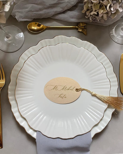 Cream Oval Place Card with gold tassel on white scalloped plate in a wedding table setting — Polina Perri
