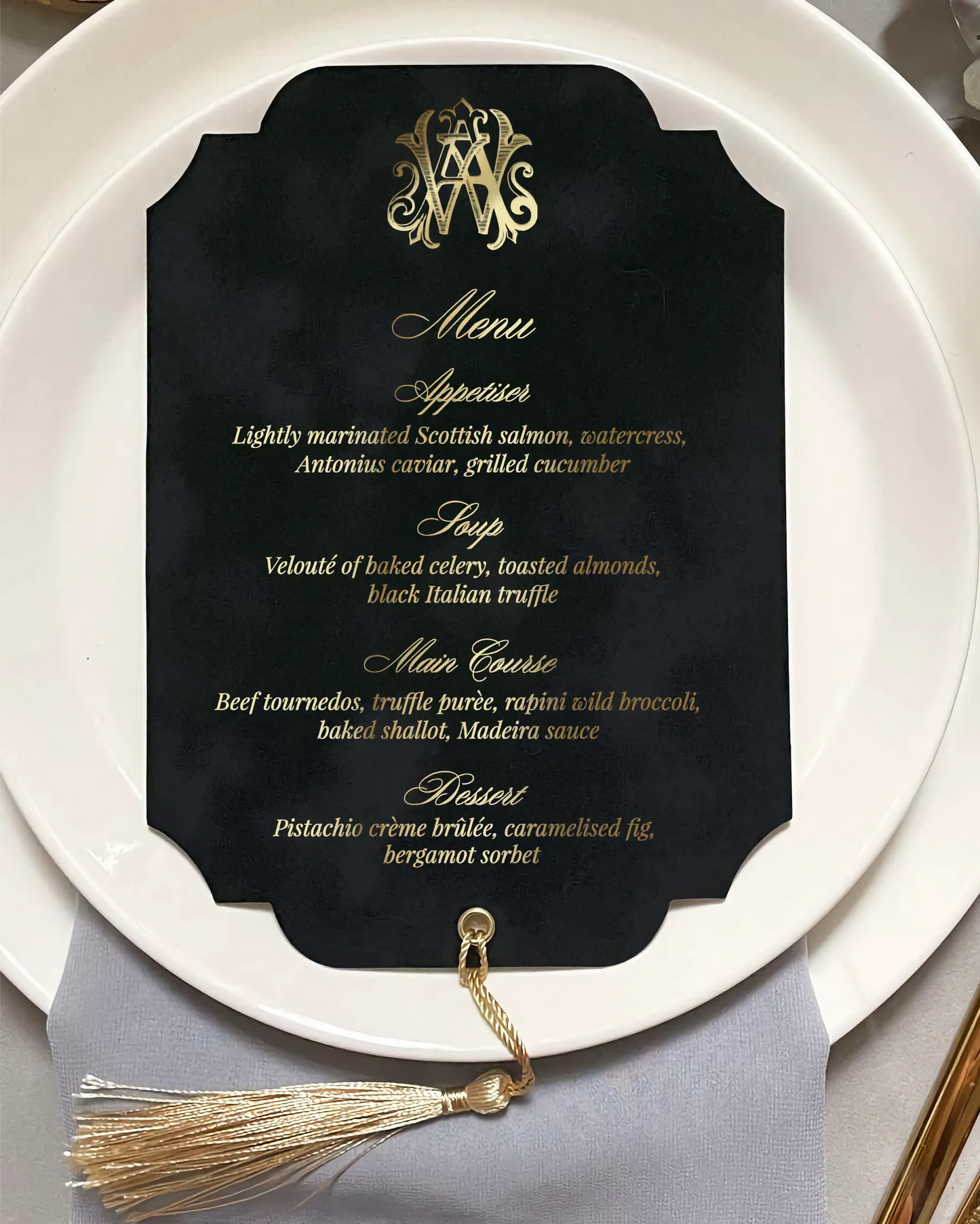 Black menu card with gold text and tassel on a white plate