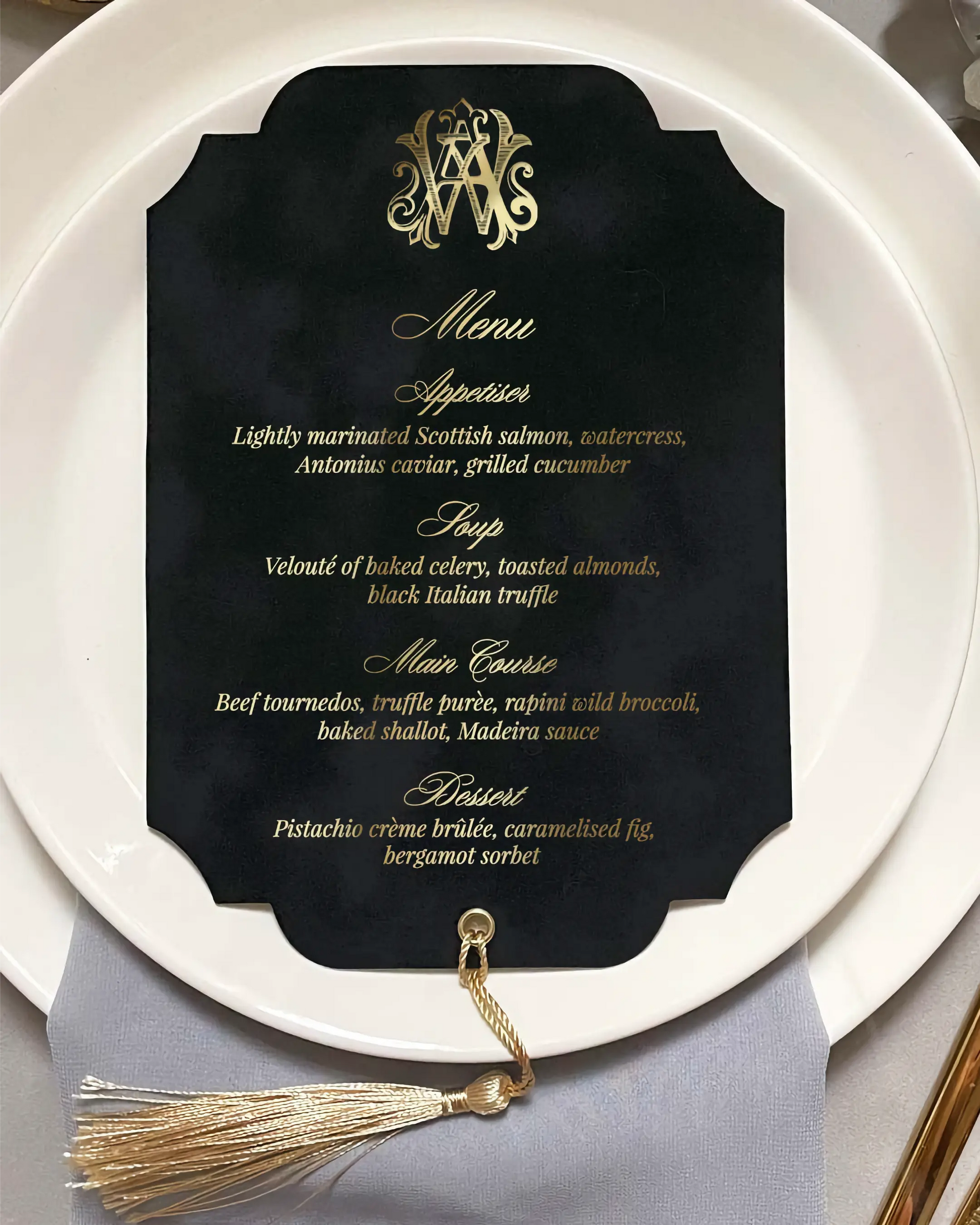 Black menu card with gold text and tassel on a white plate