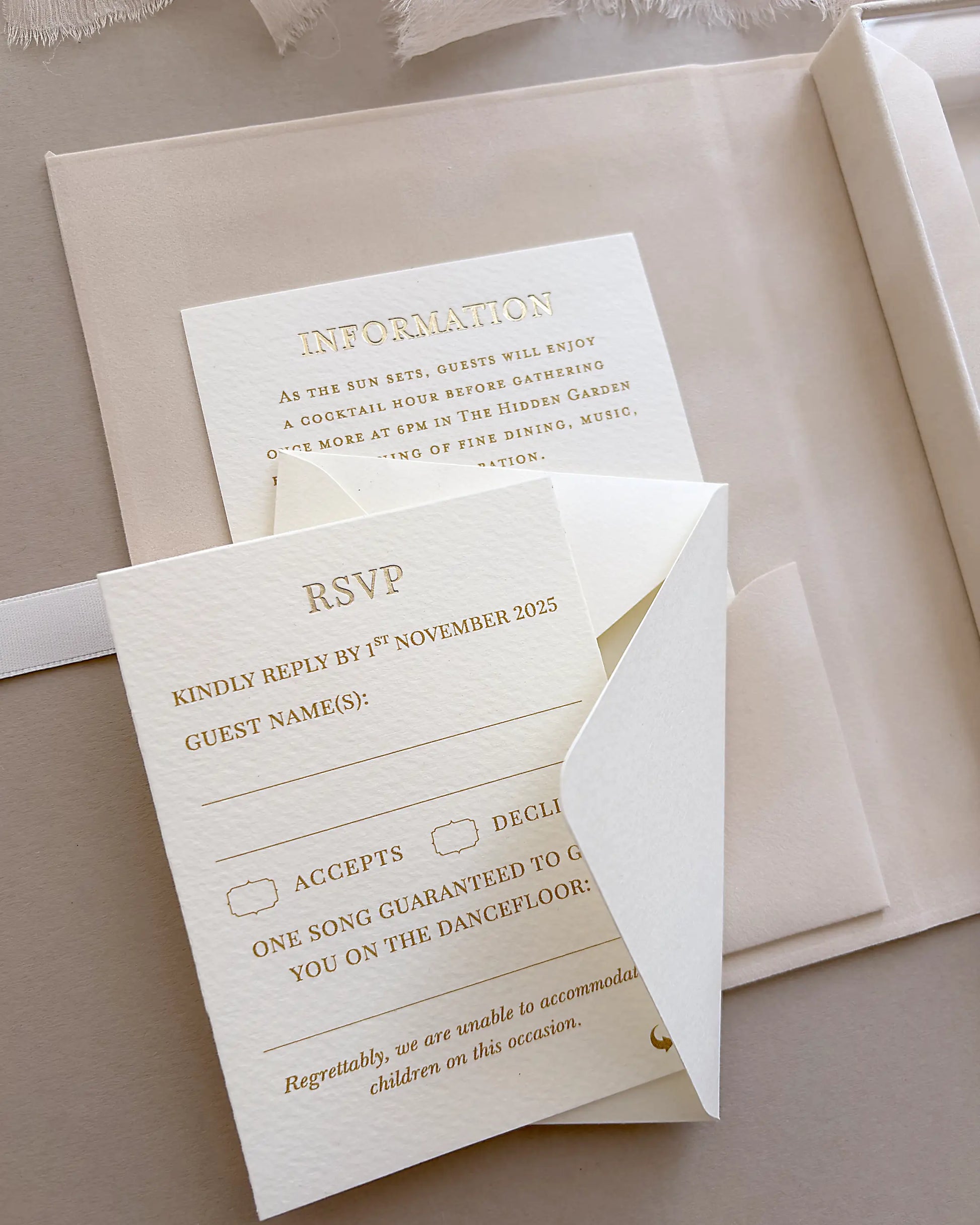 Close up of a premium textured paper RSVP wedding invitation card with elegant gold typography inside a blush velvet box suite — Polina Perri