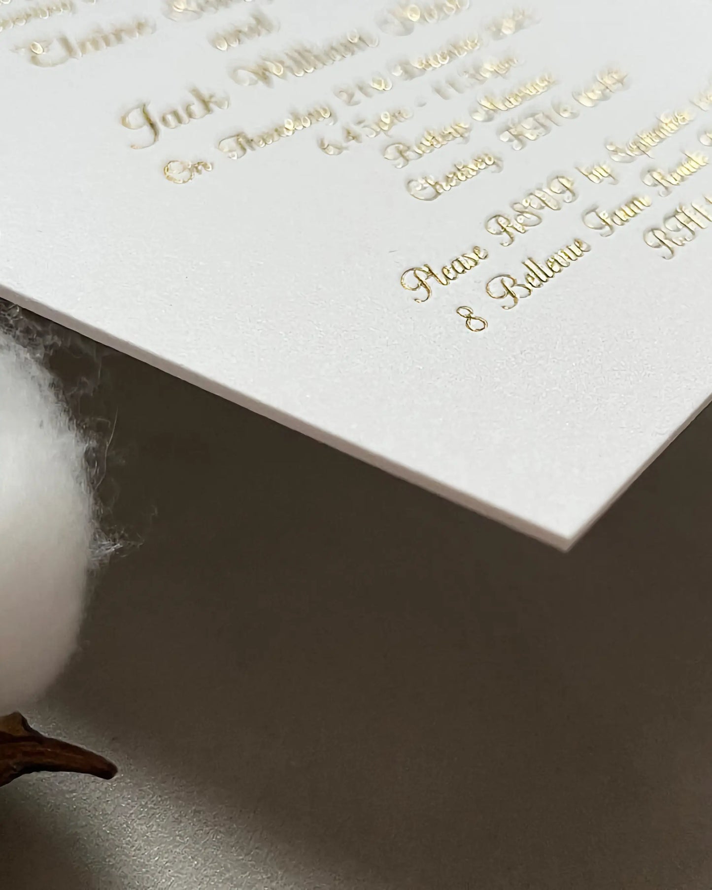 Extreme close-up of a venue wedding invitation corner, showcasing the premium tactile texture and thickness of the 600gsm cotton paper stock with crisp gold foil text — Polina Perri