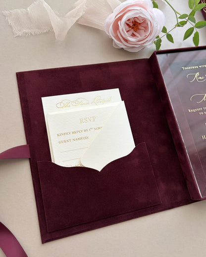Tactile texture of a burgundy velvet pocket enclosing fine wedding reply inserts, decorated with an elegant pale pink rose accent — Polina Perri