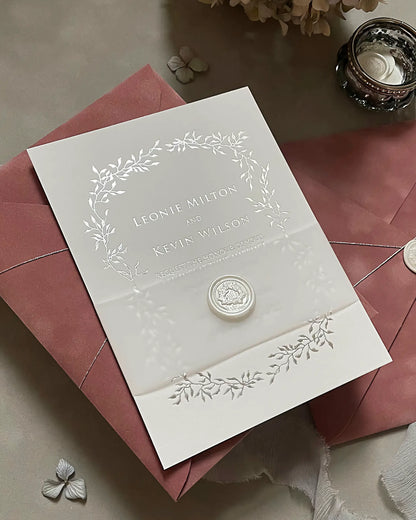 Gold foil wedding invitation card featuring a delicate leaf border on heavy cotton paper, displayed with a dusty pink envelope and white wax seal — Polina Perri