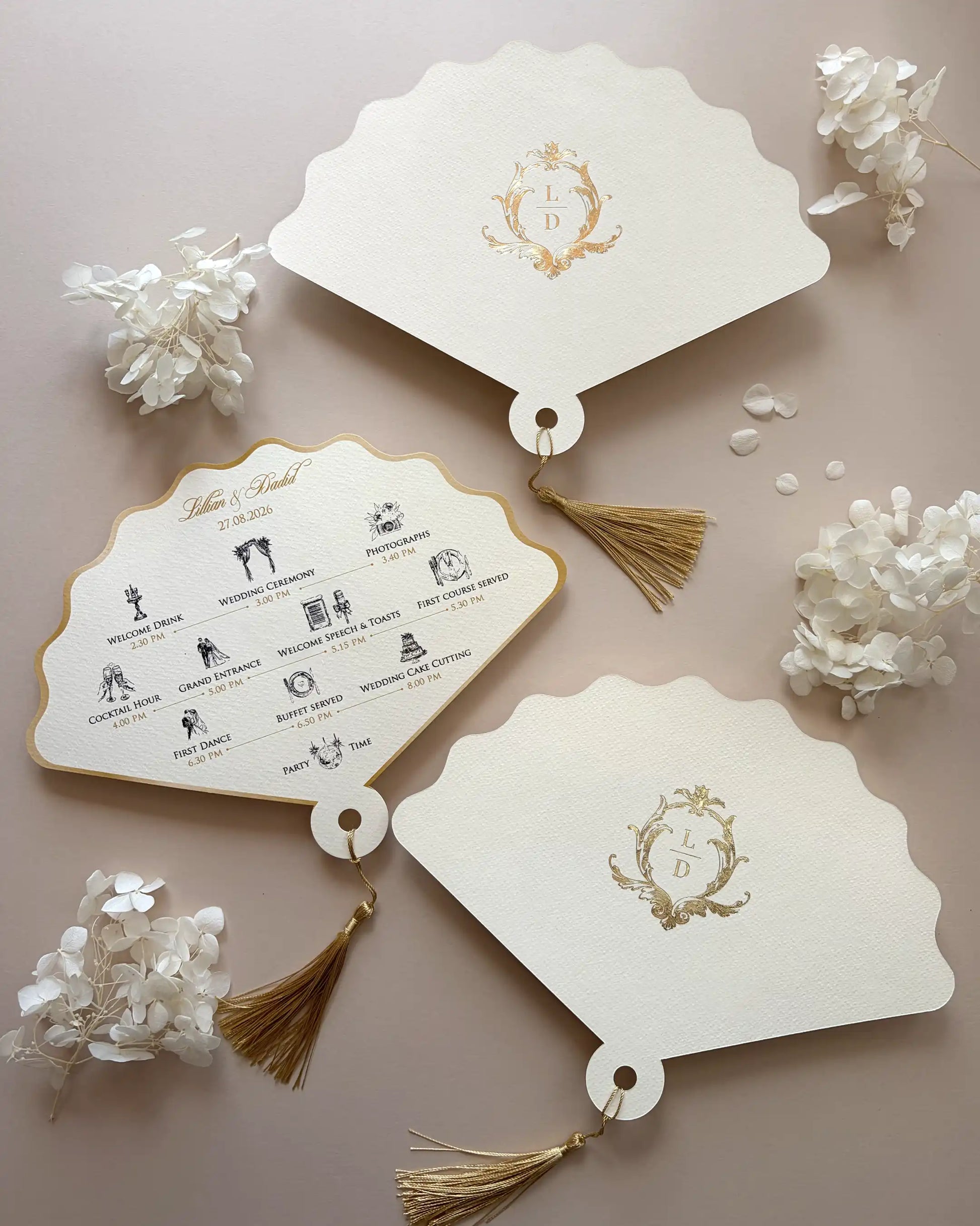 Elegant wedding order of the day printed on fan-shaped cream paper cards with a gold foil monogram, intricate timeline icons, and luxury gold tassels — Polina Perri