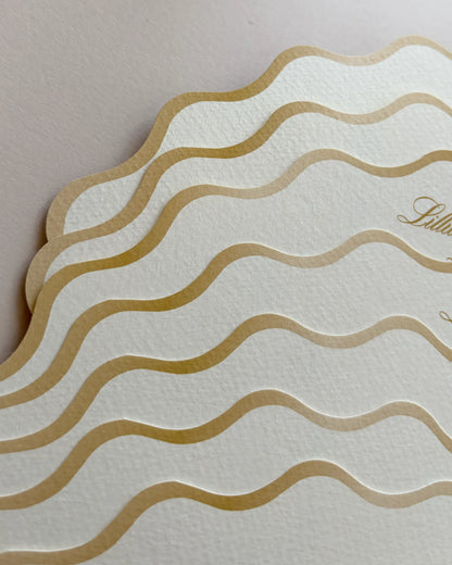 A close-up view of the decorative edge of a luxury fan wedding order of the day, showcasing elegant embossed wavy gold foil lines on high-quality cream textured paper — Polina Perri