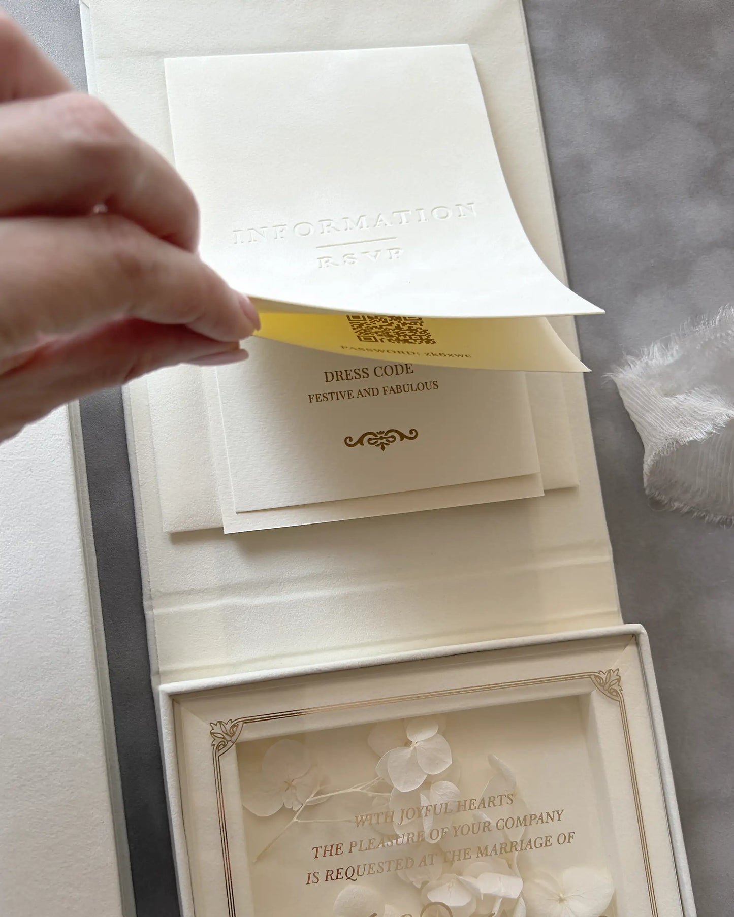 Bespoke cream velvet invitation box interior showing a dedicated pocket for inserts, with a hand lifting a gold foil pressed wedding information card — Polina Perri