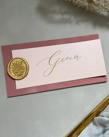 Elegant wedding groom name card crafted with a dusty rose velvet backing, fine gold foil script text on vellum, and a detailed metallic gold wax seal — Polina Perri