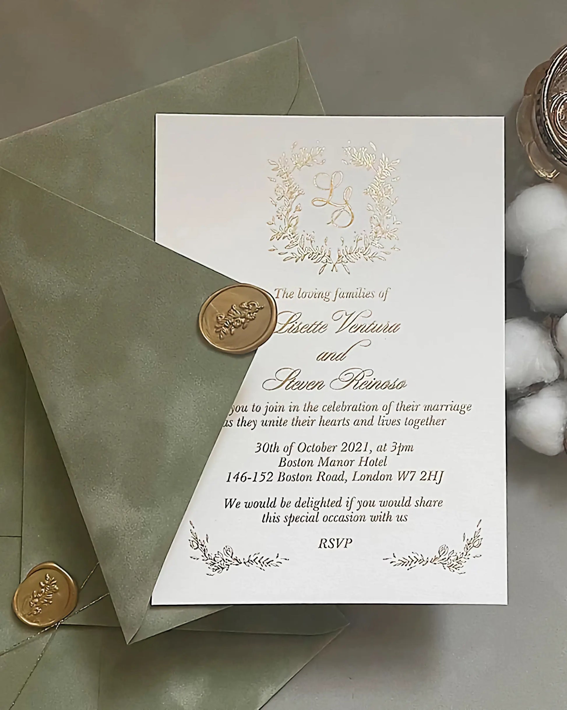 Fiori Gold foil pressed wedding invitation with a botanical floral monogram wreath on luxury white cotton paper, tucked into a sage green envelope with a gold wax seal — Polina Perri