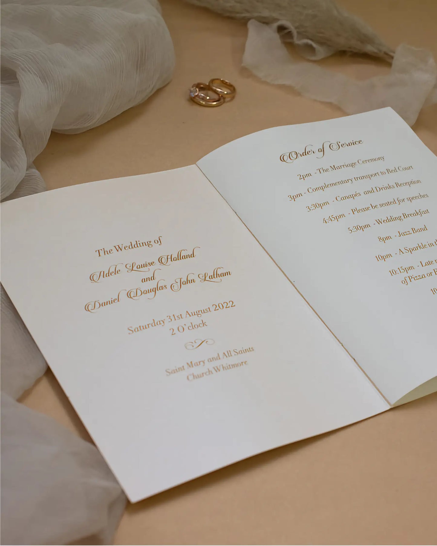 An open wedding program brochure from the Foliage range displaying the couple's names, church venue details, and the daily timeline in elegant script fonts — Polina Perri
