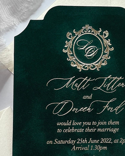 Macro shot of a forest green velvet wedding invitation showing the rich velvet fabric texture and a detailed metallic gold foil stamped crest monogram — Polina Perri