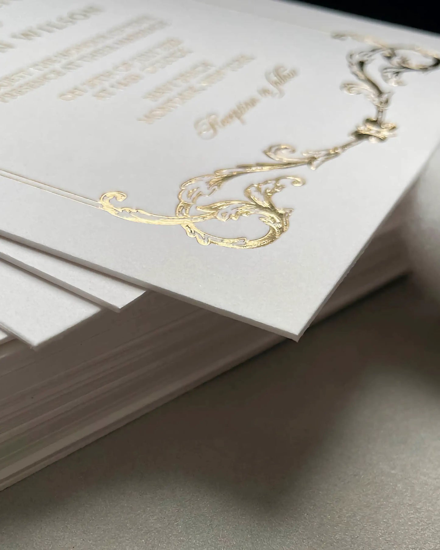 Macro shot of the Isabelle wedding invitation corner, showcasing the premium textured cotton card stock and intricate embossed gold foil baroque pattern — Polina Perri