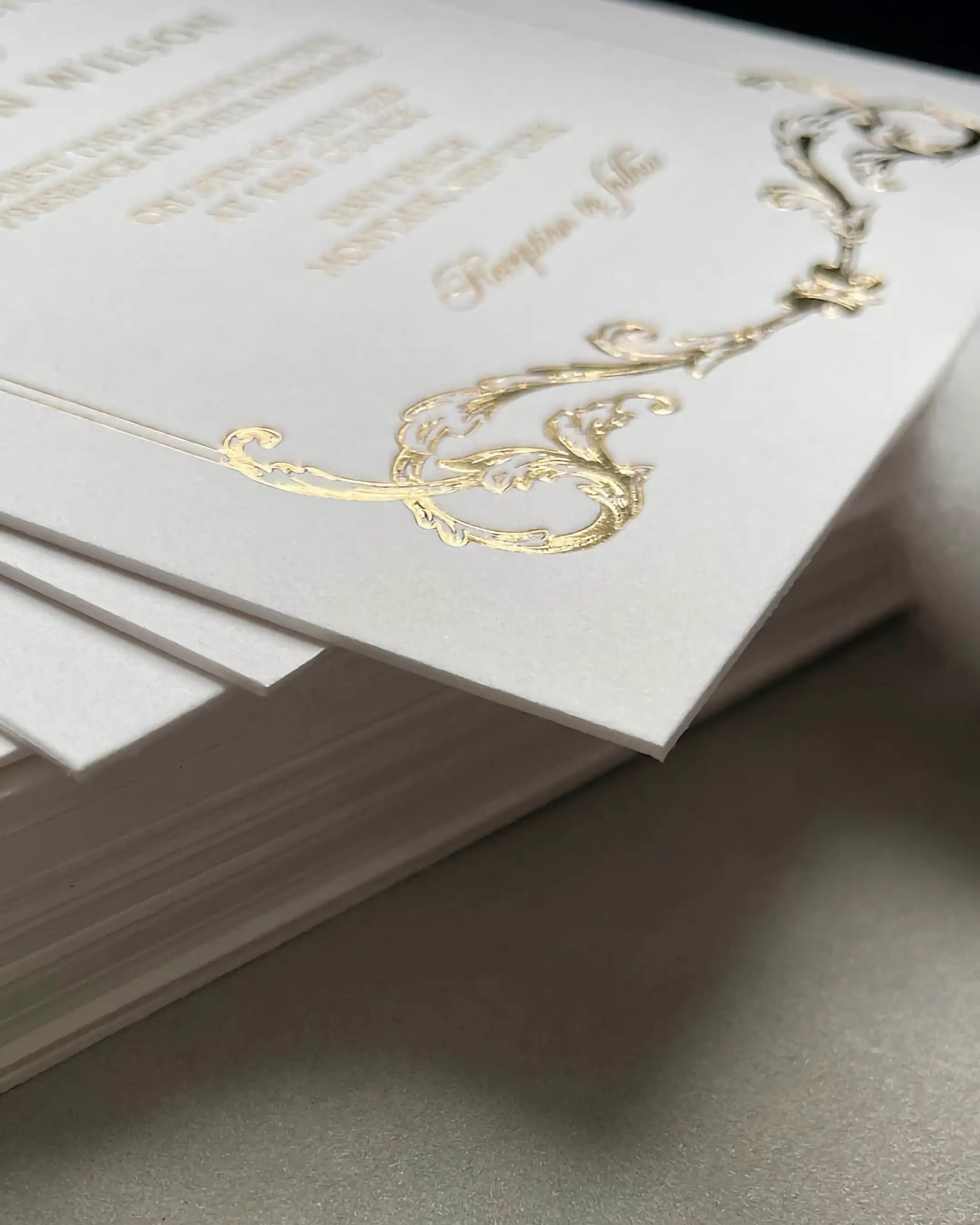 Macro shot of the Isabelle wedding invitation corner, showcasing the premium textured cotton card stock and intricate embossed gold foil baroque pattern — Polina Perri