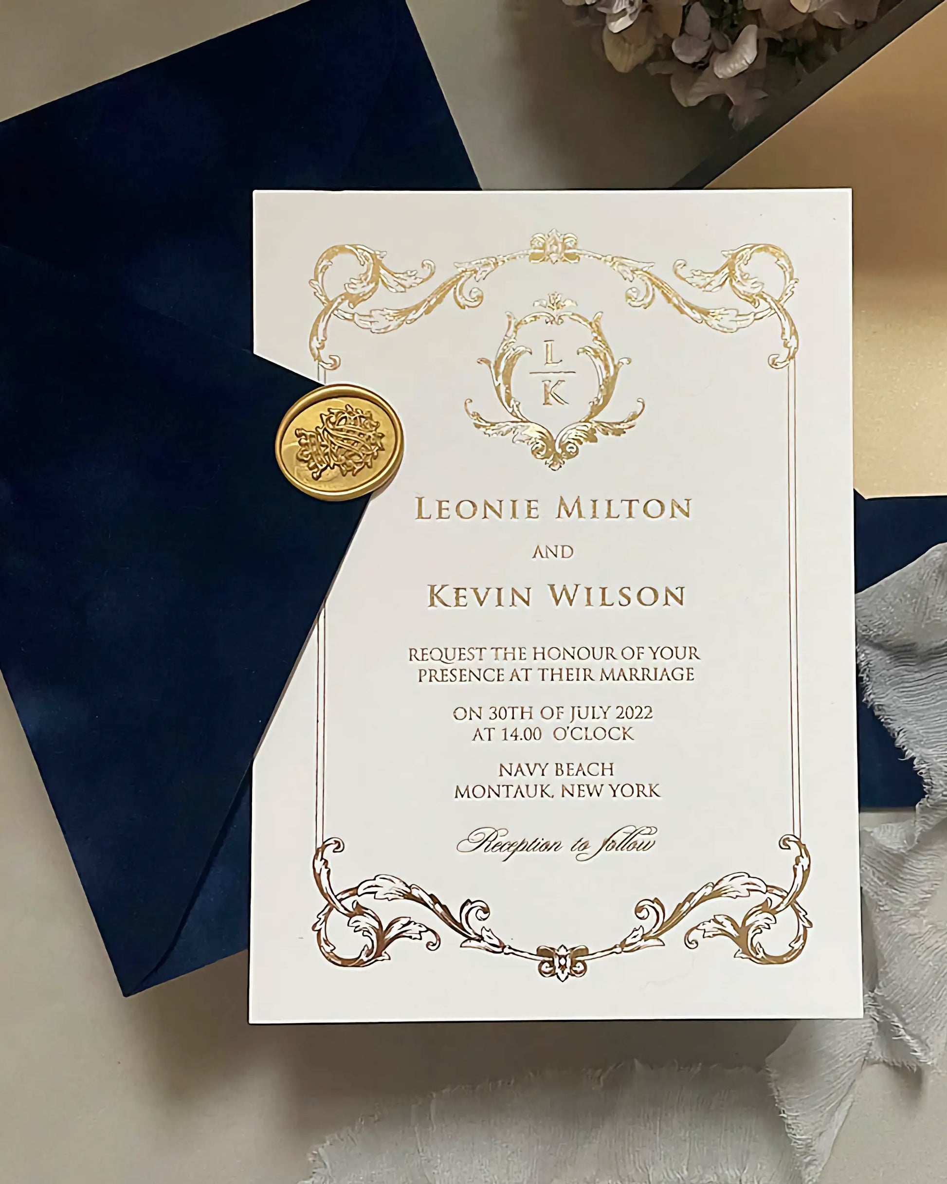 Isabelle Gold foil wedding invitation printed on 600gsm heavy cotton card stock, featuring an ornate baroque frame and a custom monogram, displayed on a textured navy blue velvet envelope with a gold wax seal — Polina Perri