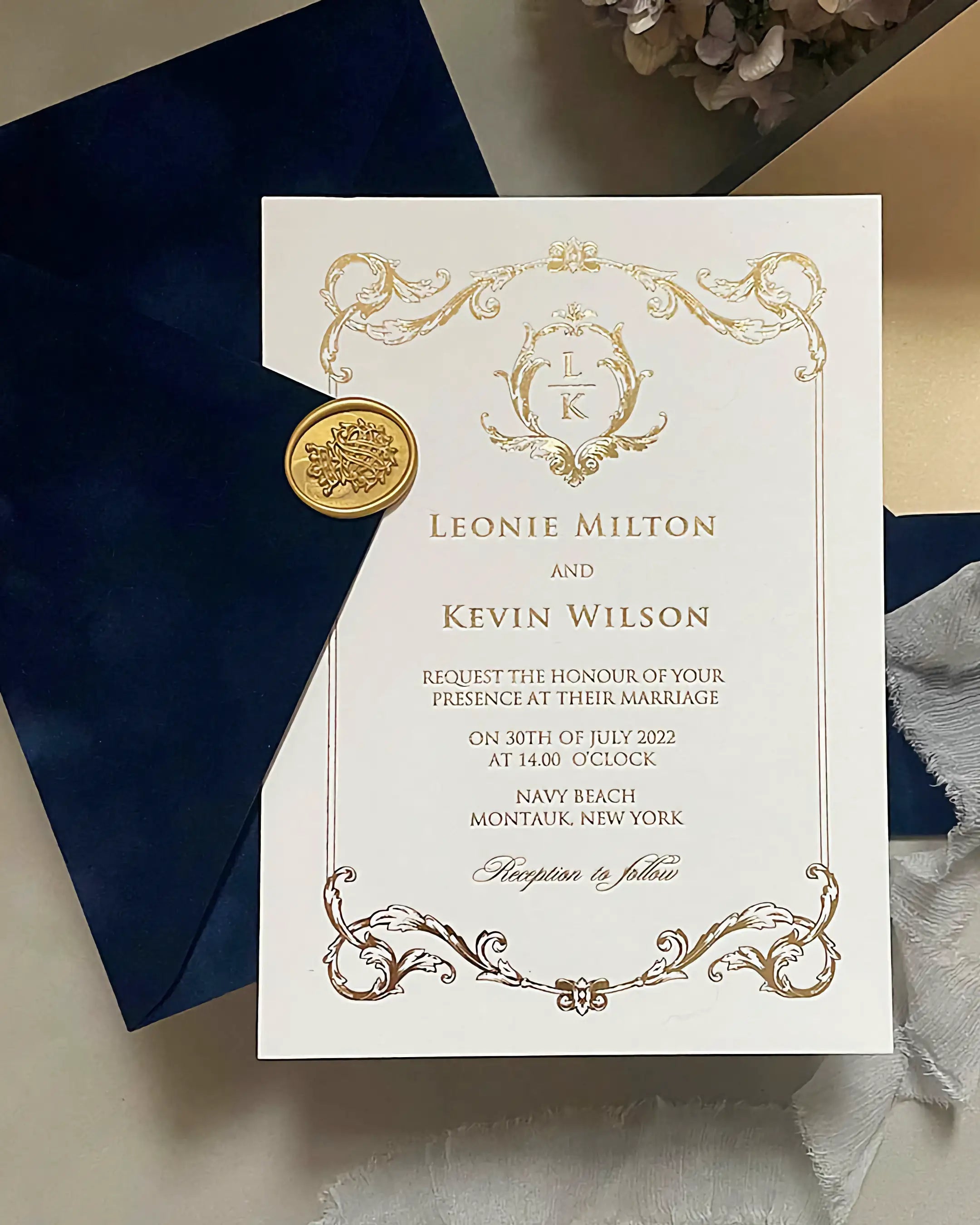 Isabelle Gold foil wedding invitation printed on 600gsm heavy cotton card stock, featuring an ornate baroque frame and a custom monogram, displayed on a textured navy blue velvet envelope with a gold wax seal — Polina Perri
