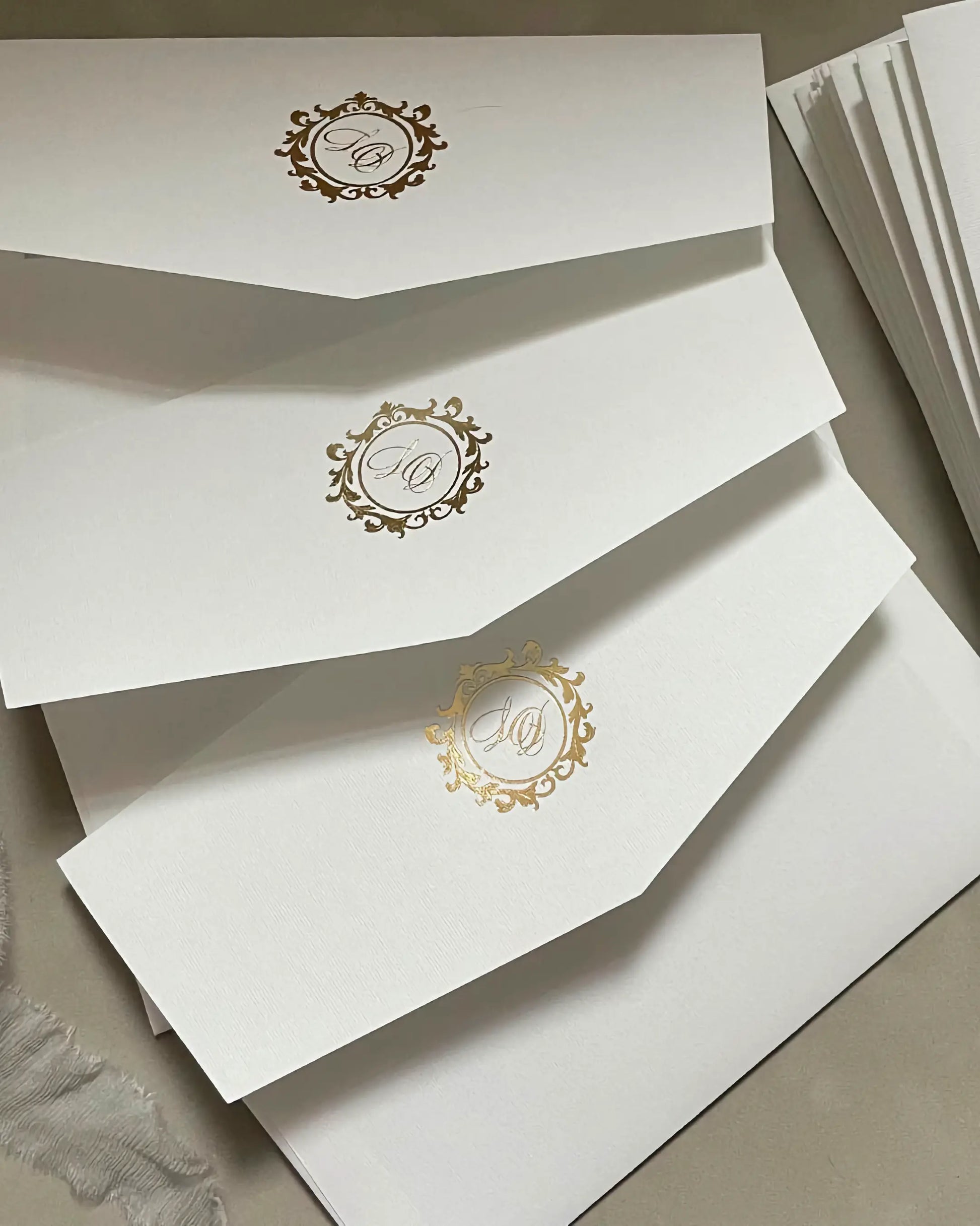Premium matte white wedding envelopes featuring bespoke gold foil pressed monogram crests on the back flaps — Polina Perri