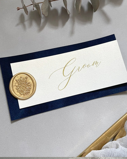 Sophisticated navy blue velvet place card showcasing a personalized translucent overlay, shimmering gold text, and a vintage-style gold wax seal impression — Polina Perri