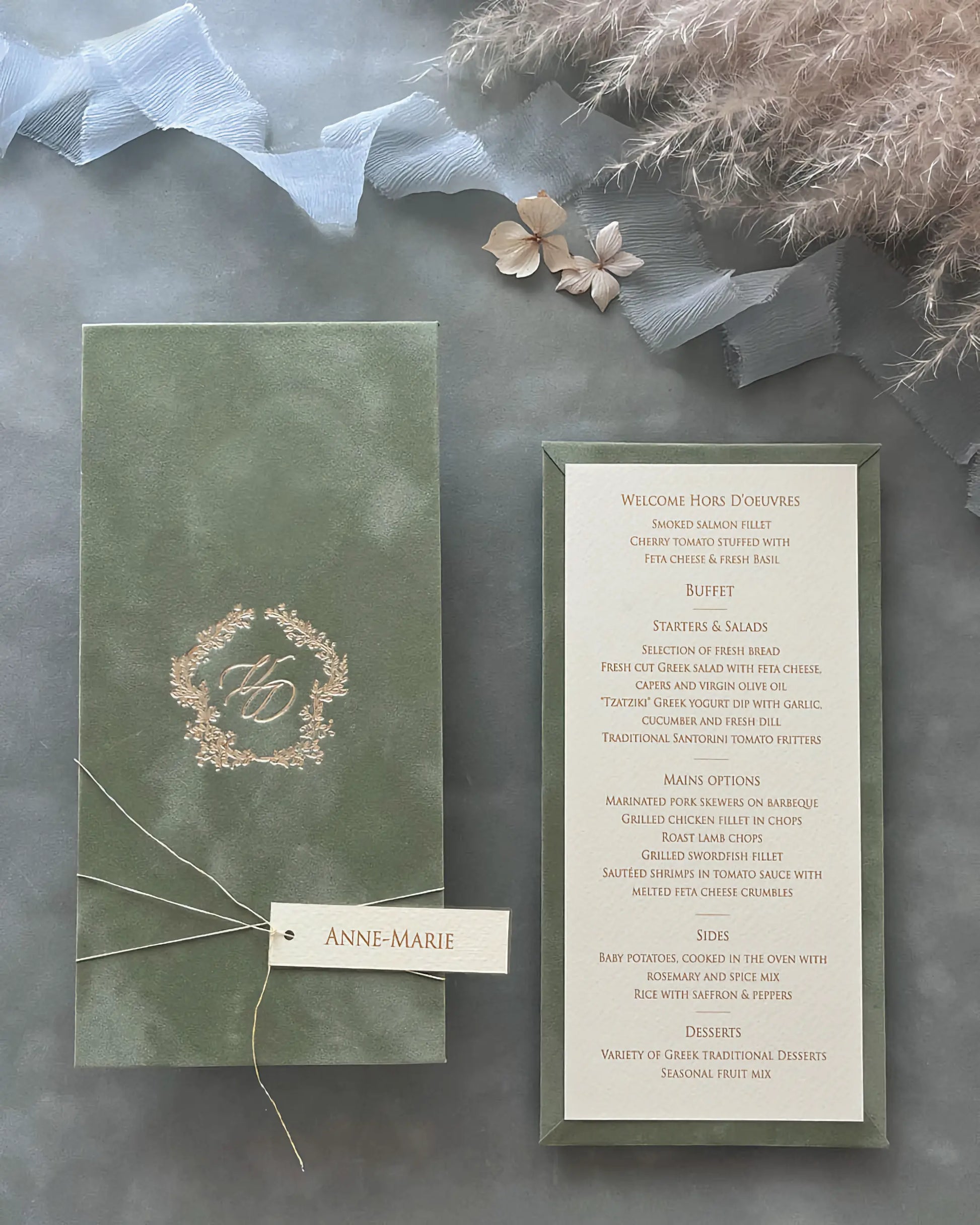 Luxury sage green velvet board wedding menu card featuring a gold foil pressed monogram crest paired with a textured insert card and custom name tag — Polina Perri