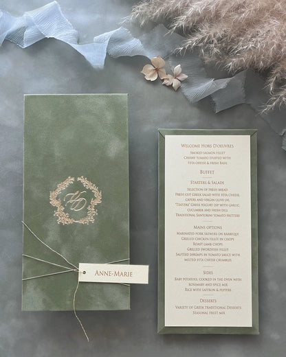 Luxury sage green velvet board wedding menu card featuring a gold foil pressed monogram crest paired with a textured insert card and custom name tag — Polina Perri
