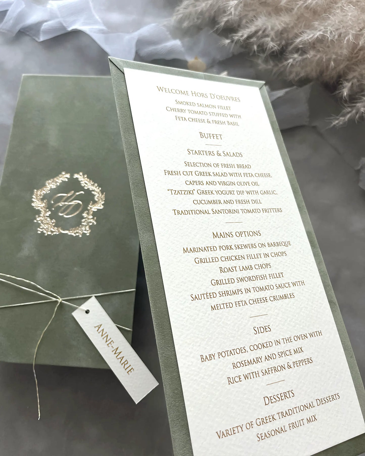 Angled shot of a sage green velvet wedding dinner menu showcasing the premium textured paper card with elegant gold typography and a personalized tag — Polina Perri