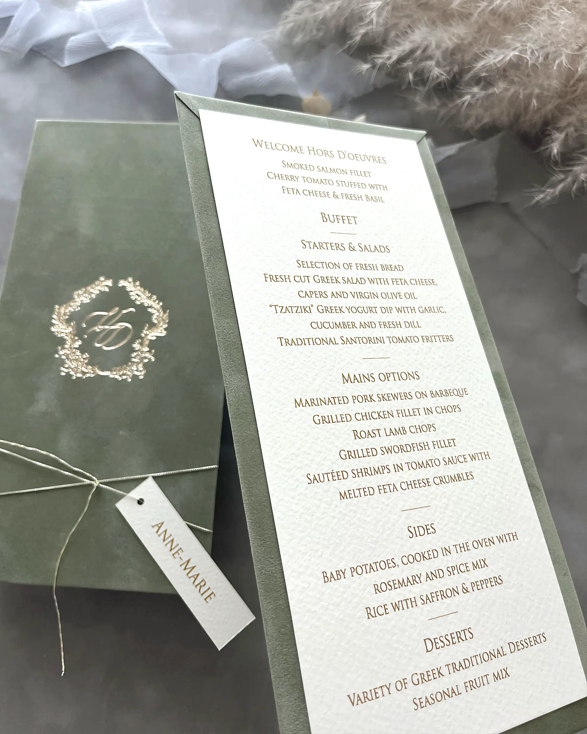 Angled shot of a sage green velvet wedding dinner menu showcasing the premium textured paper card with elegant gold typography and a personalized tag — Polina Perri