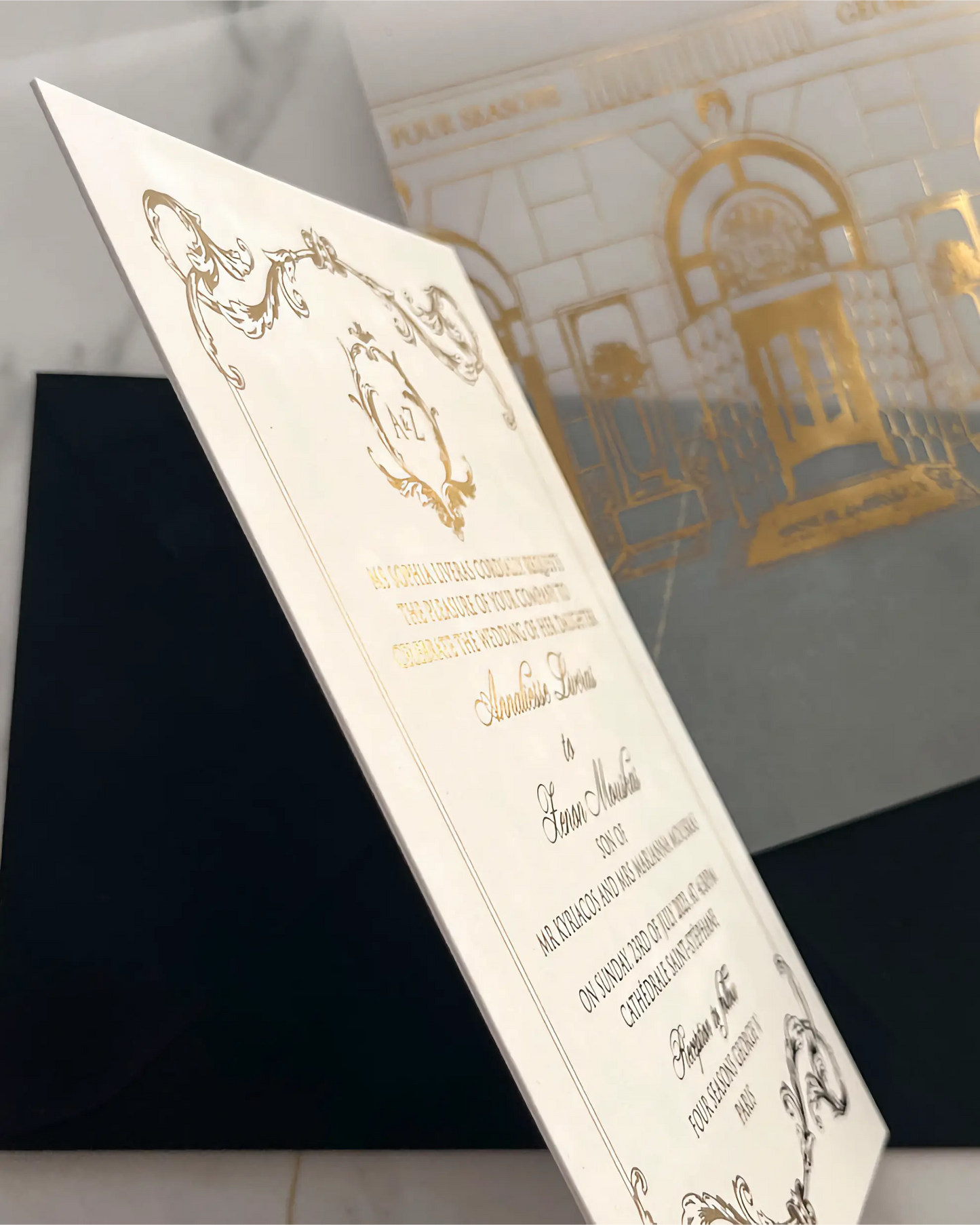 Close-up side view of a premium 600gsm thick cotton cardstock wedding invitation card displaying crisp gold foil debossed calligraphy and ornate vintage borders — Polina Perri