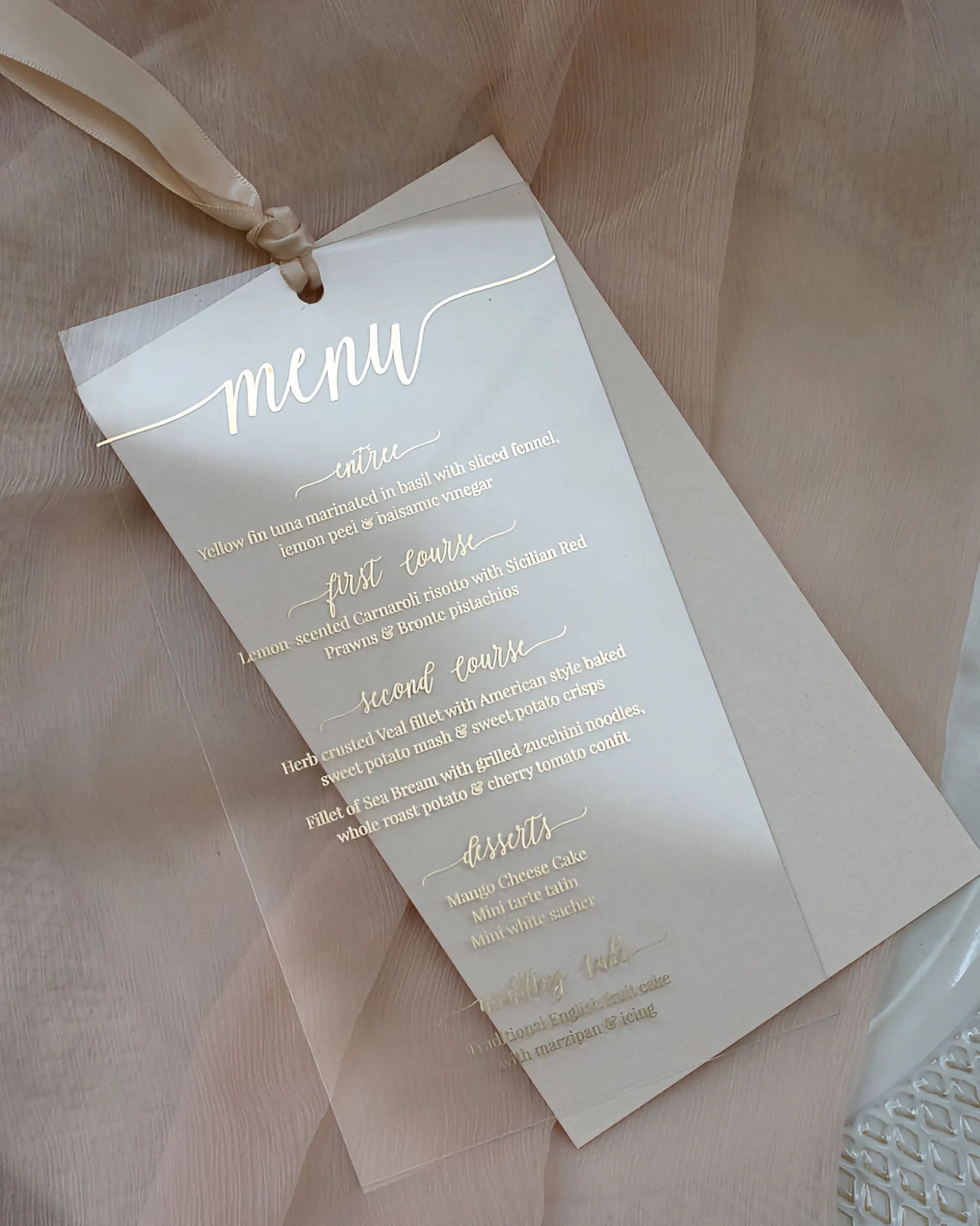 Full view of a transparent wedding dinner menu crafted from high-quality acrylic sheeting with elegant gold foil pressed lettering and a champagne ribbon — Polina Perri