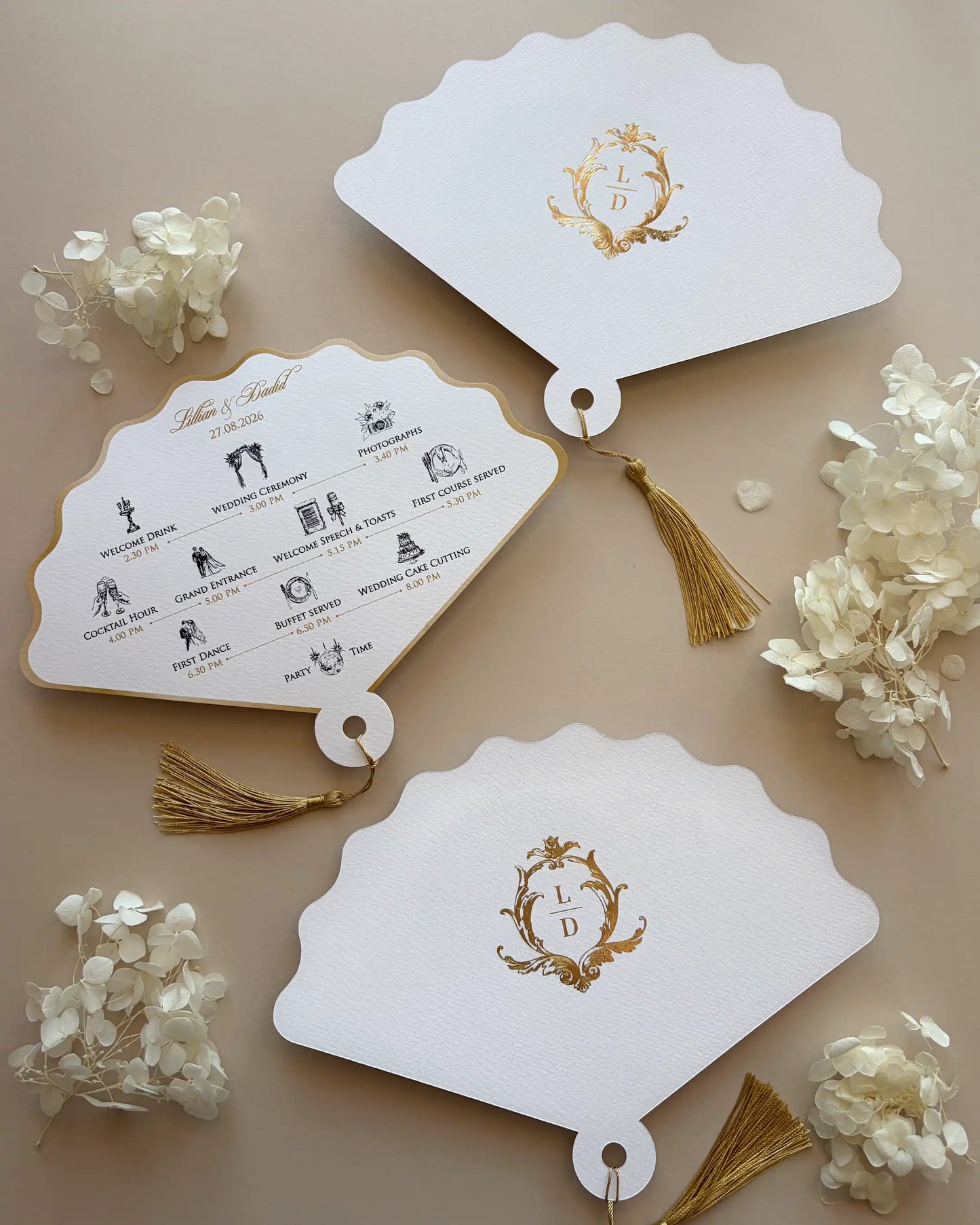 Luxury white paper fan-shaped wedding order of the day featuring a gold foil monogram, event timeline icons, and a gold tassel.