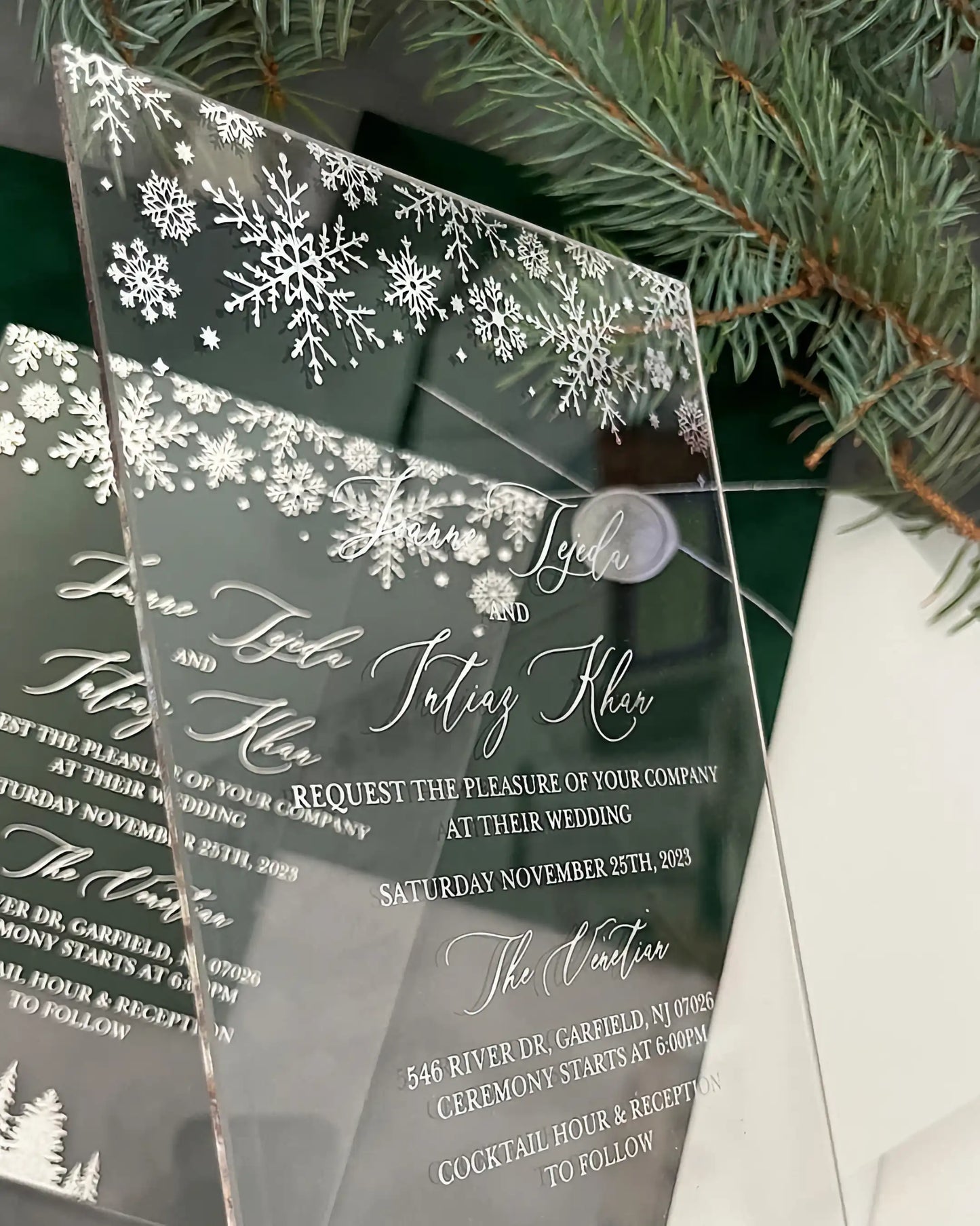 Winter Wonderland Silver Acrylic wedding invitations with silver snowflakes stacked with pine greenery — Polina Perri